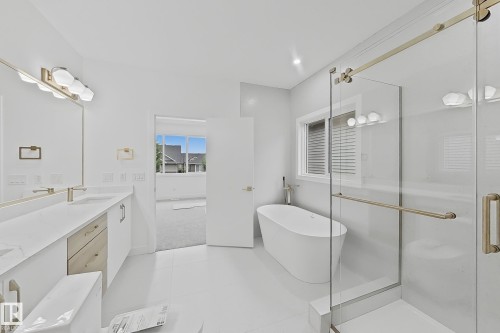 Bathroom featuring a freestanding soaking tub, a frameless glass shower enclosure, and a double vanity with quartz countertops - 8423 Mayday Link Link Sw, Edmonton, AB - Indoor Photo Showing Bathroom