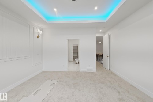 Spacious room featuring a tray ceiling with accent lighting, recessed ceiling lights, and wall sconces - 8423 Mayday Link Link Sw, Edmonton, AB - Indoor Photo Showing Other Room