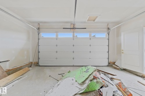 Two-car garage featuring a white panel door with upper transom windows - 8423 Mayday Link Link Sw, Edmonton, AB - Indoor Photo Showing Garage