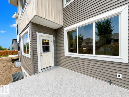 Exterior siding in a two-tone finish, featuring a ground-level patio with a textured surface - 8423 Mayday Link Link Sw, Edmonton, AB - Outdoor With Exterior
