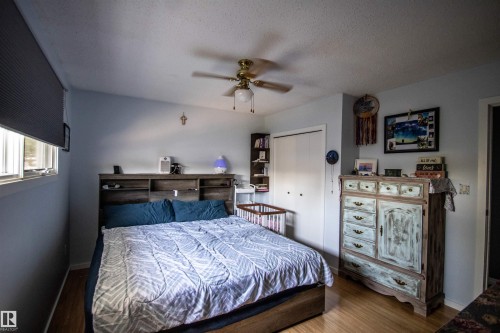 Spacious bedroom featuring wood-finish flooring, light blue walls, and a white bi-fold closet - 5017 55 Ave, St. Paul Town, AB - Indoor Photo Showing Bedroom
