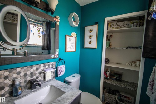 Bathroom featuring a single vanity with stone-finish countertop, undermount sink, and dark-finish faucet - 5017 55 Ave, St. Paul Town, AB - Indoor Photo Showing Bathroom
