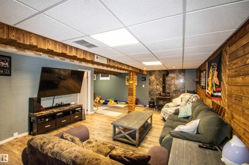 Finished lower-level space featuring wood-finish flooring and a drop ceiling with integrated lighting - 5017 55 Ave, St. Paul Town, AB - Indoor Photo Showing Basement
