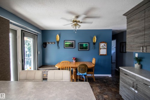 Dining area featuring a ceiling fan with integrated lighting, wood-finish flooring, and a patio door - 5017 55 Ave, St. Paul Town, AB - Indoor