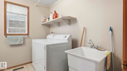 Dedicated utility room featuring a window with wood trim, ceramic tile flooring, built-in shelving, and a utility sink with a chrome faucet - 
