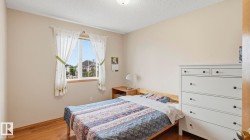 Bedroom featuring a large window, neutral wall paint, textured ceiling, and wood-finish flooring - 