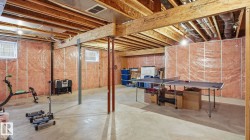 Unfinished basement offering expansive open space, concrete flooring, exposed wooden beams, and multiple windows for natural light - 