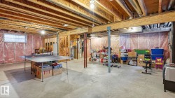 Expansive unfinished basement featuring exposed wood joists, concrete flooring, and partial framing with insulation - 