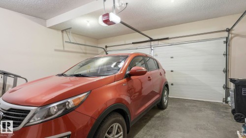 Attached garage with a white sectional door, concrete flooring, and overhead lighting - 125 Dechene Road Nw, Edmonton, AB - Indoor Photo Showing Garage