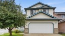 Two-story residence featuring light-colored siding with dark trim accents, an attached garage, and brick detailing on the facade - 125 Dechene Road Nw, Edmonton, AB  - Outdoor 
