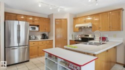 Kitchen featuring wood cabinetry, stainless steel appliances, a double basin sink, and track lighting - 