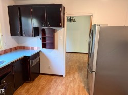 Kitchen featuring dark cabinetry, laminate countertops, and wood-finish flooring - 