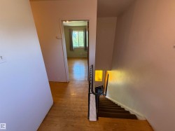 Wood-finish flooring throughout the hallway and visible room, complemented by a white baseboard trim - 