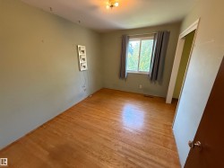 Room with wood-finish flooring, a window offering natural light, and a ceiling-mounted light fixture - 