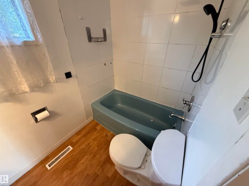 Bathroom featuring wood-finish flooring, a blue tub, white tiled shower surround, and a white toilet - 14 Gillian Crescent, St. Albert, AB - Indoor Photo Showing Bathroom