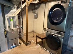 Dedicated utility area featuring a stacked washer and dryer unit, a furnace, and a water heater - 