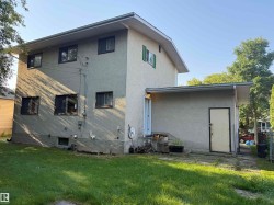 Two-story stucco exterior with multiple windows and a lower level access door - 