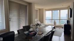 Open concept living space featuring a dining area and a living area with large windows, wood-finish flooring, and recessed lighting - 