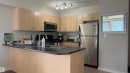 Kitchen featuring light wood-finish cabinetry, stainless steel appliances, and a peninsula with a dark countertop - #2401 10180 104 St Nw, Edmonton, AB  - Indoor Photo Showing Kitchen With Double Sink 