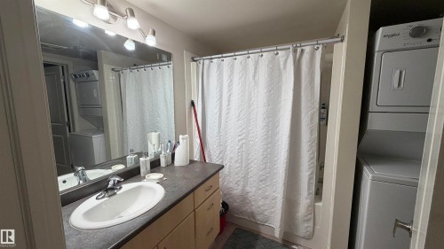 Bathroom featuring a vanity with an oval sink, chrome faucet, and dark-finish countertop - #2401 10180 104 St Nw, Edmonton, AB - Indoor Photo Showing Bathroom