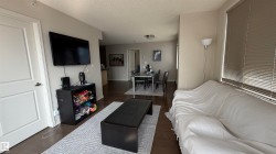Open-concept living area with wood-finish flooring, neutral wall tones, and horizontal window blinds - 