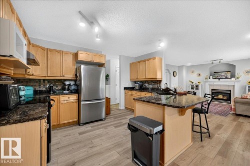 Kitchen featuring wood-finish flooring and light wood cabinetry - 6 Norfolk Close, St. Albert, AB - Indoor Photo Showing Kitchen With Fireplace