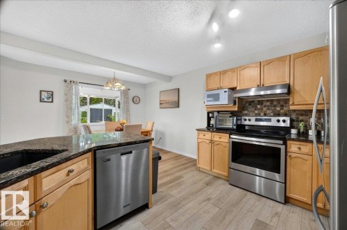 Kitchen featuring wood-finish cabinetry, dark granite countertops, stainless steel appliances, and a mosaic tile backsplash - 6 Norfolk Close, St. Albert, AB - Indoor Photo Showing Kitchen