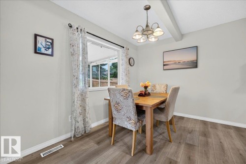 Dining area featuring wood-finish flooring, a contemporary chandelier, a window with exterior views, and white baseboards - 6 Norfolk Close, St. Albert, AB - Indoor Photo Showing Dining Room