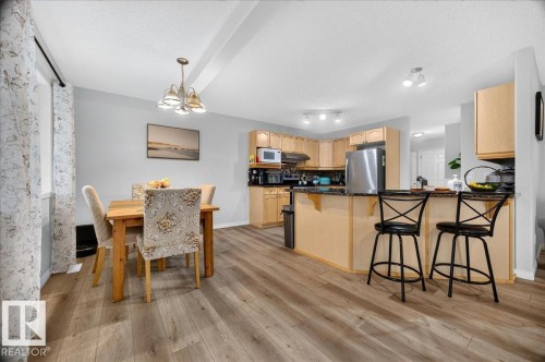 Open-concept kitchen and dining area featuring wood-finish flooring, light wood cabinetry, stainless steel appliances, and a granite-look countertop - 6 Norfolk Close, St. Albert, AB - Indoor