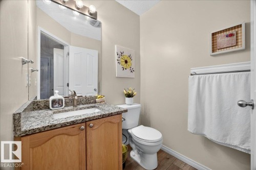 Bathroom featuring a vanity with a granite countertop, undermount sink, wood-finish cabinetry, and contemporary faucet - 6 Norfolk Close, St. Albert, AB - Indoor Photo Showing Bathroom