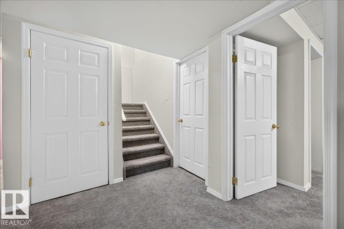 Carpeted hallway with white six-panel doors and a carpeted staircase - 6 Norfolk Close, St. Albert, AB - Indoor Photo Showing Other Room