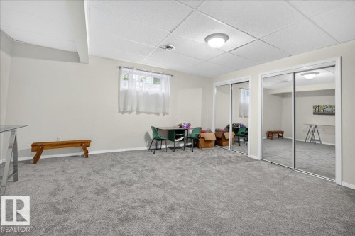 Spacious room featuring light gray carpeting, neutral wall color, two mirrored sliding closet doors, a white drop ceiling with recessed lighting, and a window with sheer white curtains - 6 Norfolk Close, St. Albert, AB - Indoor Photo Showing Other Room