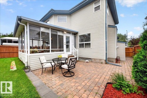 Brick paver patio with a screened-in sunroom, light-colored siding, and a manicured lawn - 6 Norfolk Close, St. Albert, AB - Outdoor