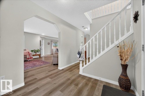 Foyer featuring wood-finish flooring, a white-spindled staircase, and arched entryways to additional living spaces - 6 Norfolk Close, St. Albert, AB - Indoor Photo Showing Other Room