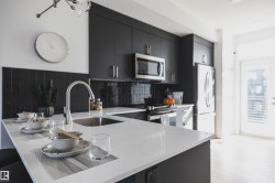 Modern kitchen featuring a white countertop island with an undermount sink and gooseneck faucet - 