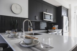 Modern kitchen featuring a white countertop island with an undermount sink and gooseneck faucet - 
