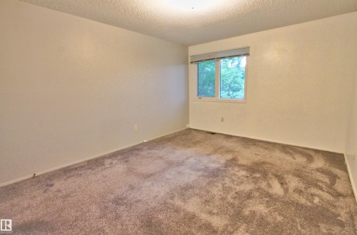 Neutral-toned carpeted room with light-colored walls, featuring a window with a blind - #302 47 Akins Dr, St. Albert, AB - Indoor Photo Showing Other Room