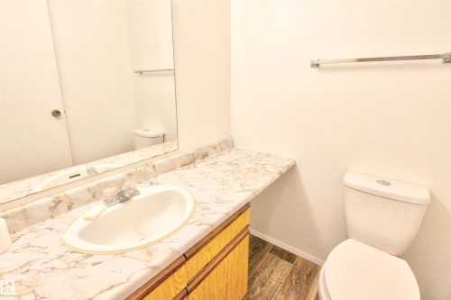 Bathroom vanity featuring an oval undermount sink, patterned countertop, wood-finish cabinetry, and a chrome faucet - #302 47 Akins Dr, St. Albert, AB - Indoor Photo Showing Bathroom