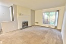 Carpeted living space featuring a white brick fireplace with a dark-toned hearth - #302 47 Akins Dr, St. Albert, AB  - Indoor With Fireplace 