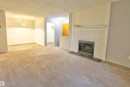 Living area featuring a white brick fireplace with a dark-toned hearth - #302 47 Akins Dr, St. Albert, AB  - Indoor Photo Showing Living Room With Fireplace 