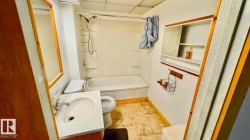 Full bathroom featuring a white vanity with integrated sink, chrome faucet, and wood-finish cabinetry - 
