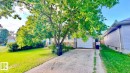 Split-level residence featuring a white garage door and a front facade with white siding and stone accents - 5144 37 Avenue Nw, Edmonton, AB  - Outdoor 