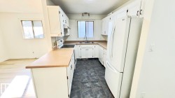 Kitchen featuring white cabinetry, light countertops, and dark tile flooring - 