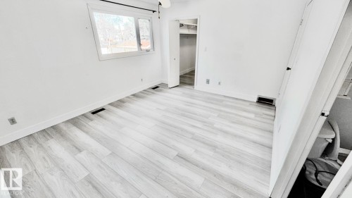 Spacious room featuring light wood-finish flooring, white baseboards, and a window with white trim - 5144 37 Avenue Nw, Edmonton, AB - Indoor Photo Showing Other Room