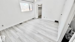 Spacious room featuring light wood-finish flooring, white baseboards, and a window with white trim - 