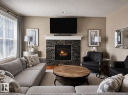 Stacked stone fireplace with a white mantel, framed by neutral tone walls - 
