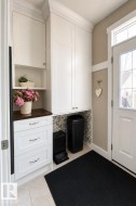 Entryway featuring custom white cabinetry with crown molding, a dark wood-finish countertop, and tile flooring - 