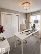 Plush carpeting and a contemporary drum chandelier illuminate this versatile room, featuring a window with blinds and full-length drapes, and paneled bi-fold doors - 