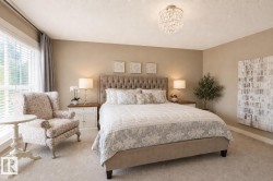 Bedroom featuring a large window, a tufted headboard, and a crystal chandelier - 