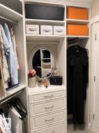 Custom closet system featuring white cabinetry, multiple hanging rods, and integrated shelving - 